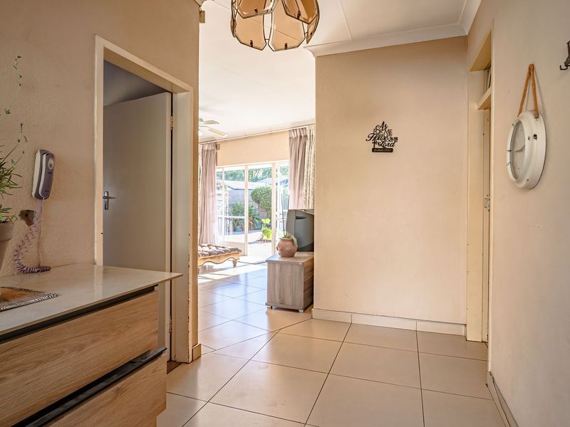 A bright, tiled hallway providing access to adjacent living areas, featuring neutral wall tones and standard internal door frames.