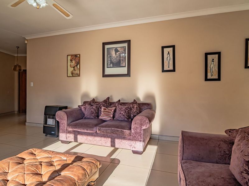 A spacious living room featuring neutral wall tones, tiled flooring, and a ceiling fan, offering a comfortable and well-lit area for relaxation.