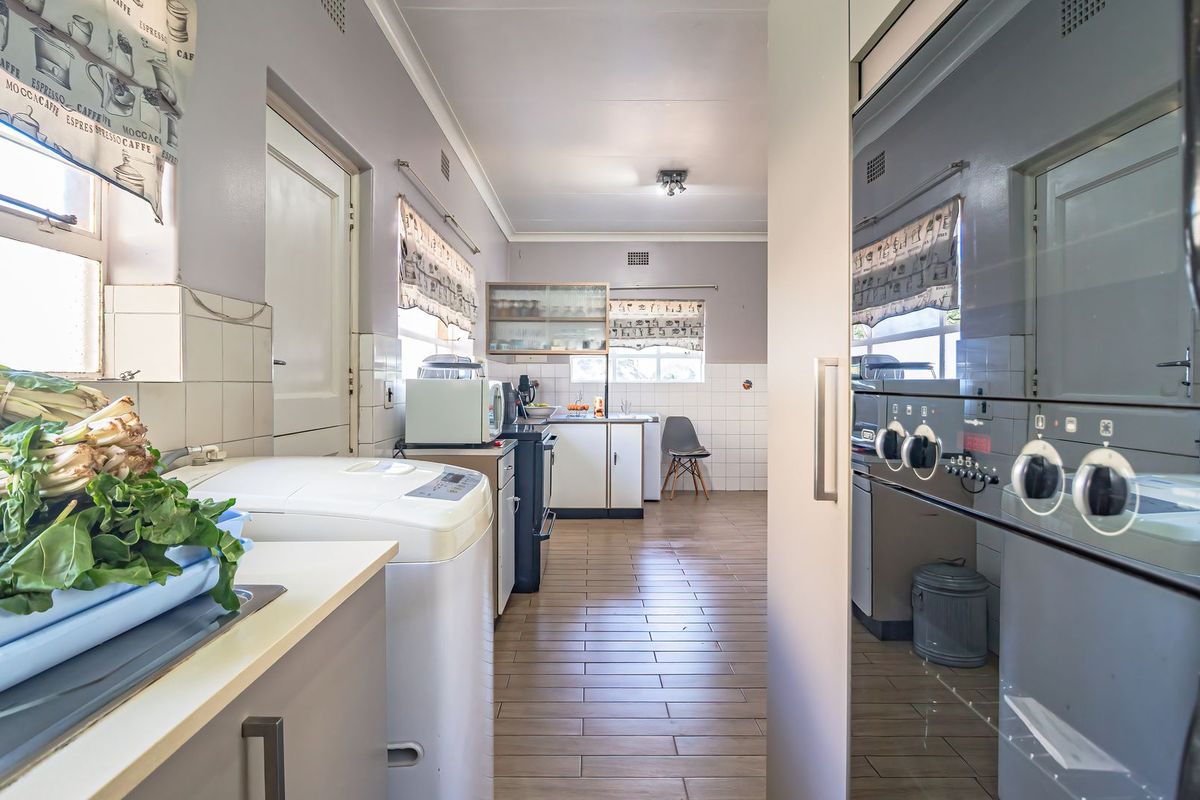A functional kitchen featuring tiled flooring, built-in cabinetry, a tiled splashback, and an integrated oven, offering a practical layout for daily meal preparation.