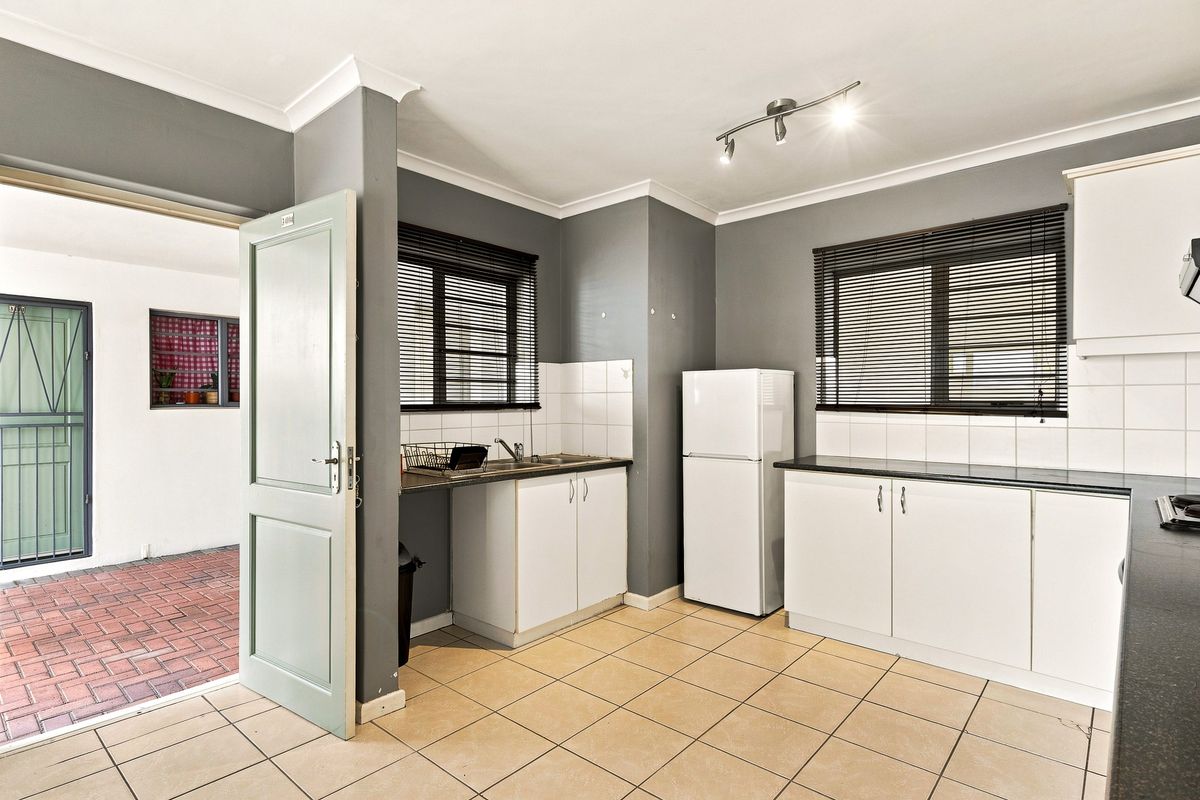 A functional kitchen featuring white cabinetry, dark countertops, tiled flooring, and direct access to an outdoor patio area.