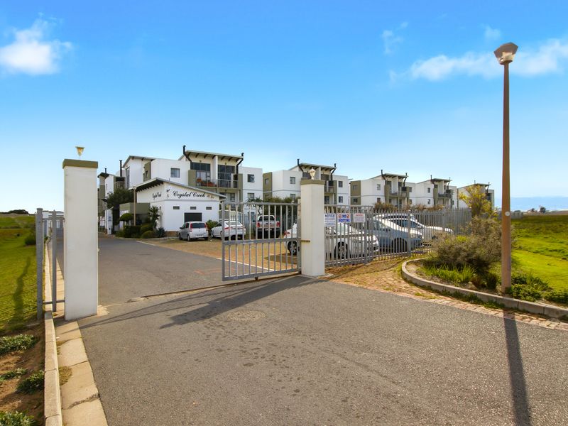 View of the secure gated entrance and driveway leading to the Crystal Creek apartment complex.