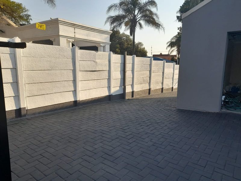 A clean, paved rear courtyard area featuring a well-maintained precast concrete boundary wall and integrated electric fencing.