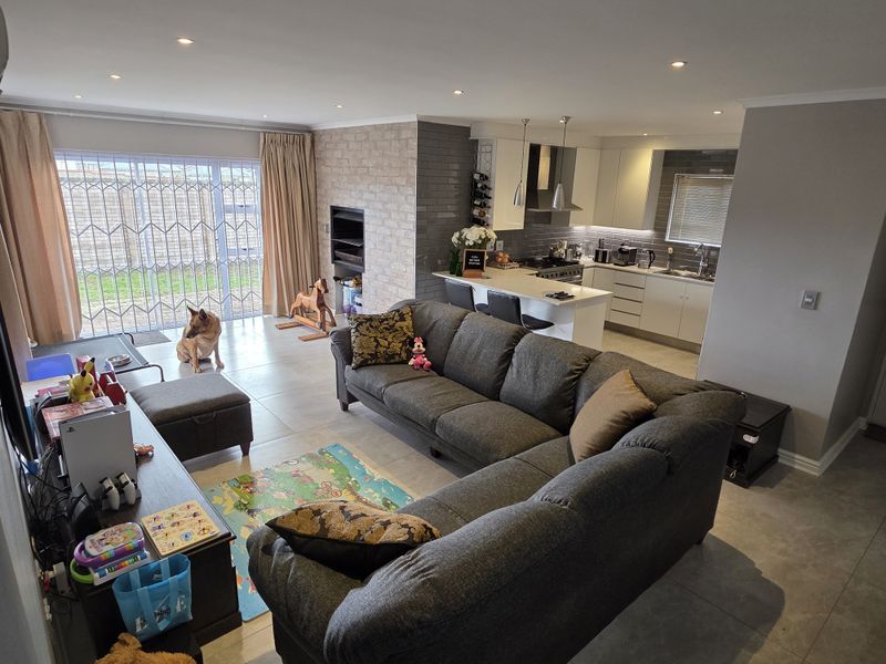 Spacious open-plan living area featuring a modern kitchen with island, stone-clad fireplace, and large sliding doors leading to the rear garden.