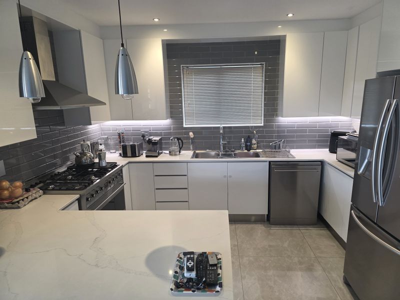 Modern kitchen featuring white cabinetry, quartz countertops, subway tile backsplash, gas cooktop, and integrated stainless steel appliances with recessed lighting.