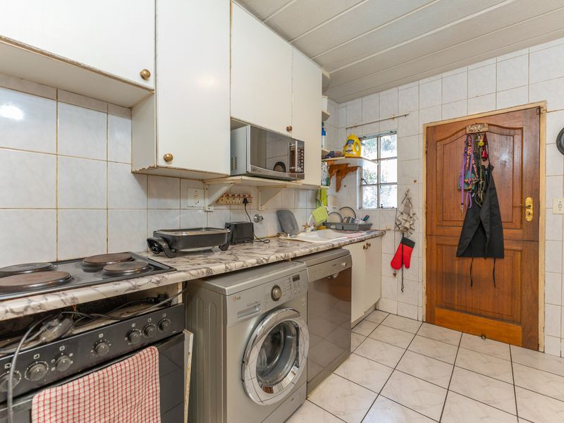 A functional kitchen featuring tiled walls and flooring, built-in cabinetry, and an integrated stove, offering a practical layout for daily meal preparation.