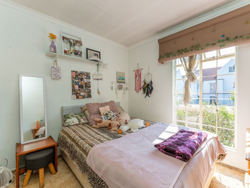 A bright bedroom featuring a large window, neutral wall finishes, and carpeted flooring, offering a comfortable and well-lit living space.