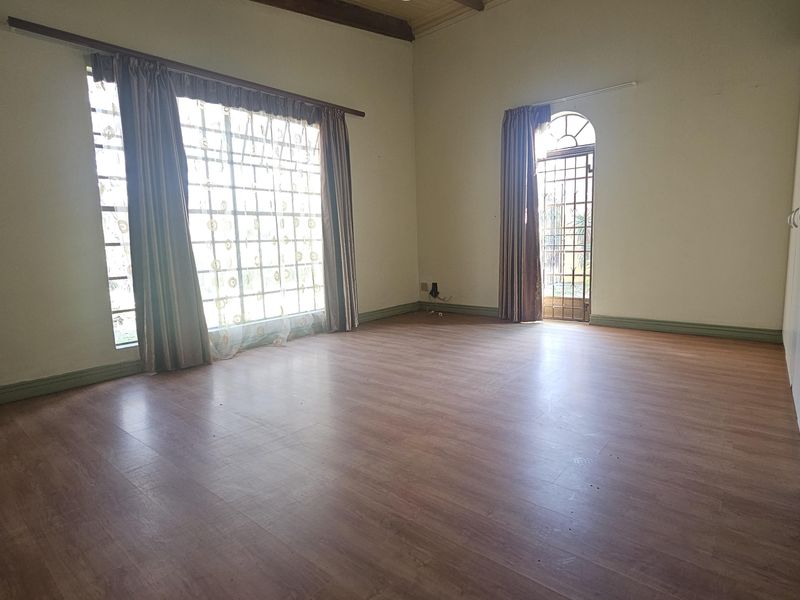 Spacious bedroom featuring laminate flooring, built-in cupboards, vaulted ceilings, and direct access to the exterior through a secure door.