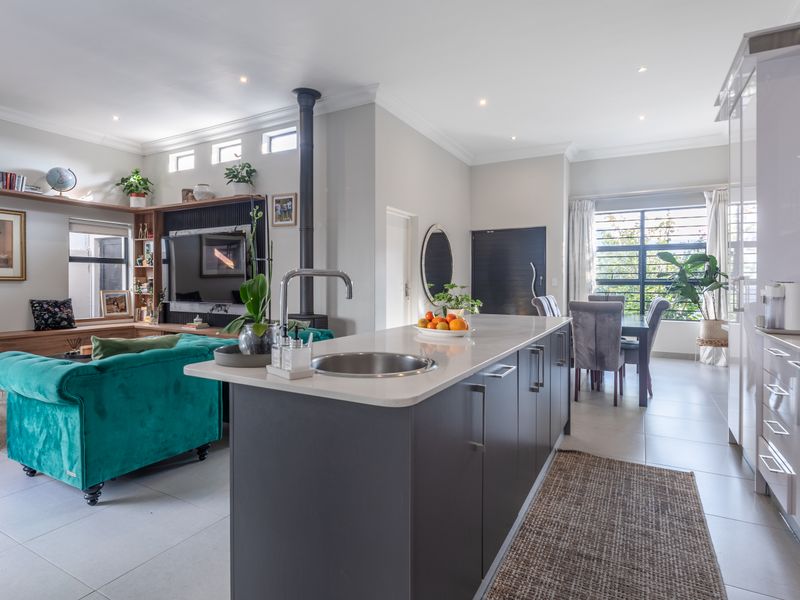Modern open-plan living area featuring a sleek kitchen with a central island, built-in appliances, and a cozy wood-burning fireplace in the adjacent lounge.