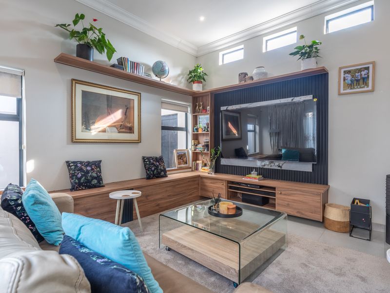 Modern living room featuring custom built-in cabinetry, floating shelving, clerestory windows for natural light, and a sleek freestanding fireplace.
