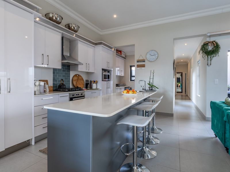 Modern open-plan kitchen featuring a central island with quartz countertops, sleek cabinetry, built-in appliances, and seamless flow into the adjacent living area.