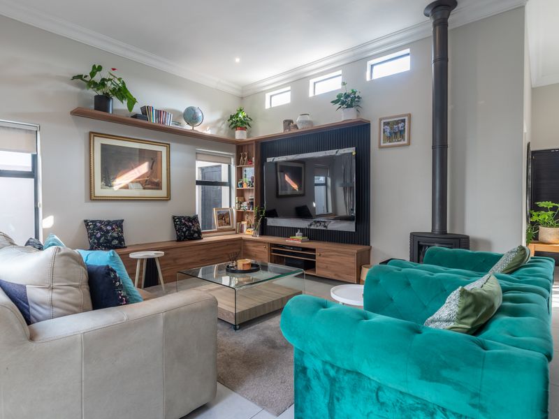 A modern, well-lit living room featuring a sleek freestanding fireplace, custom built-in cabinetry with floating shelves, and high-quality tiled flooring.