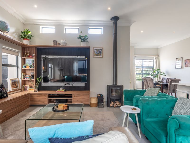 Spacious open-plan living area featuring built-in cabinetry, a modern freestanding fireplace, and clerestory windows that provide excellent natural light.