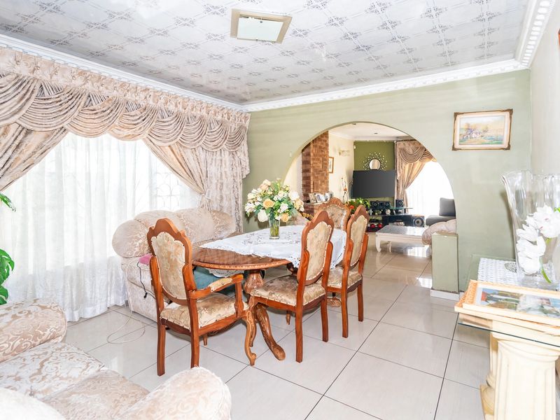 Open plan living and dining area featuring tiled flooring, an arched transition between spaces, and decorative ceiling detailing.