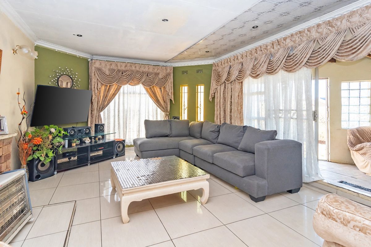 Spacious living room featuring large format floor tiles, decorative ceiling detailing, and sliding door access to the outdoor area.