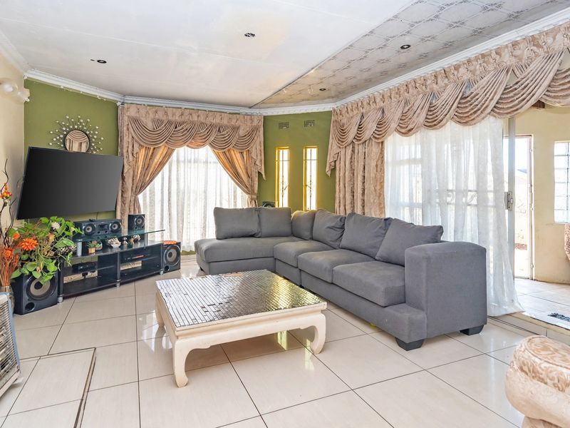 Spacious living room featuring large format floor tiles, decorative ceiling detailing, and sliding door access to the outdoor area.