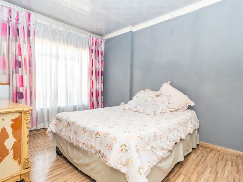 A bedroom featuring laminate flooring, decorative ceiling tiles, and crown molding, offering a functional space ready for cosmetic updates.