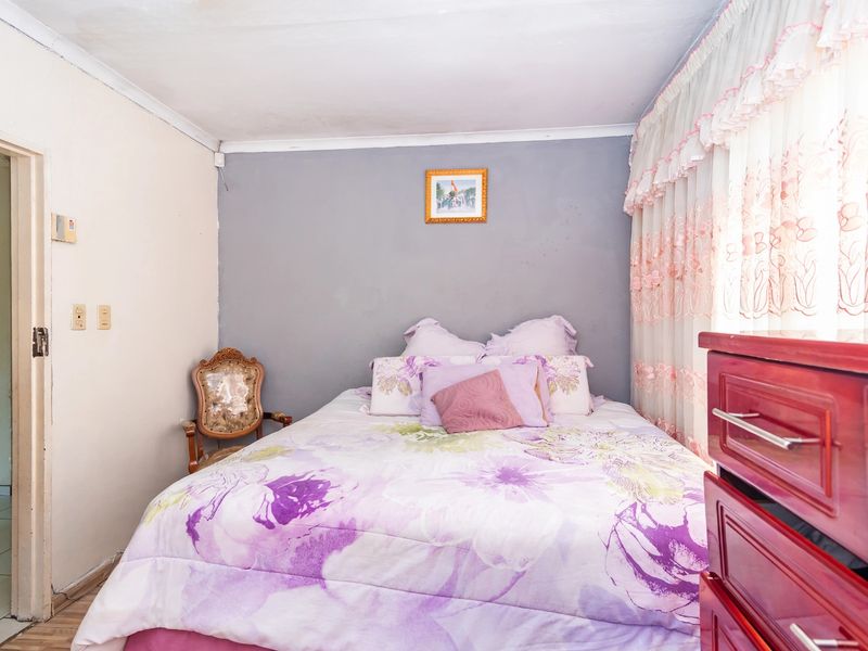 A bedroom featuring a grey accent wall, coving, and standard electrical fixtures. The space would benefit from cosmetic updates to the wall finishes.