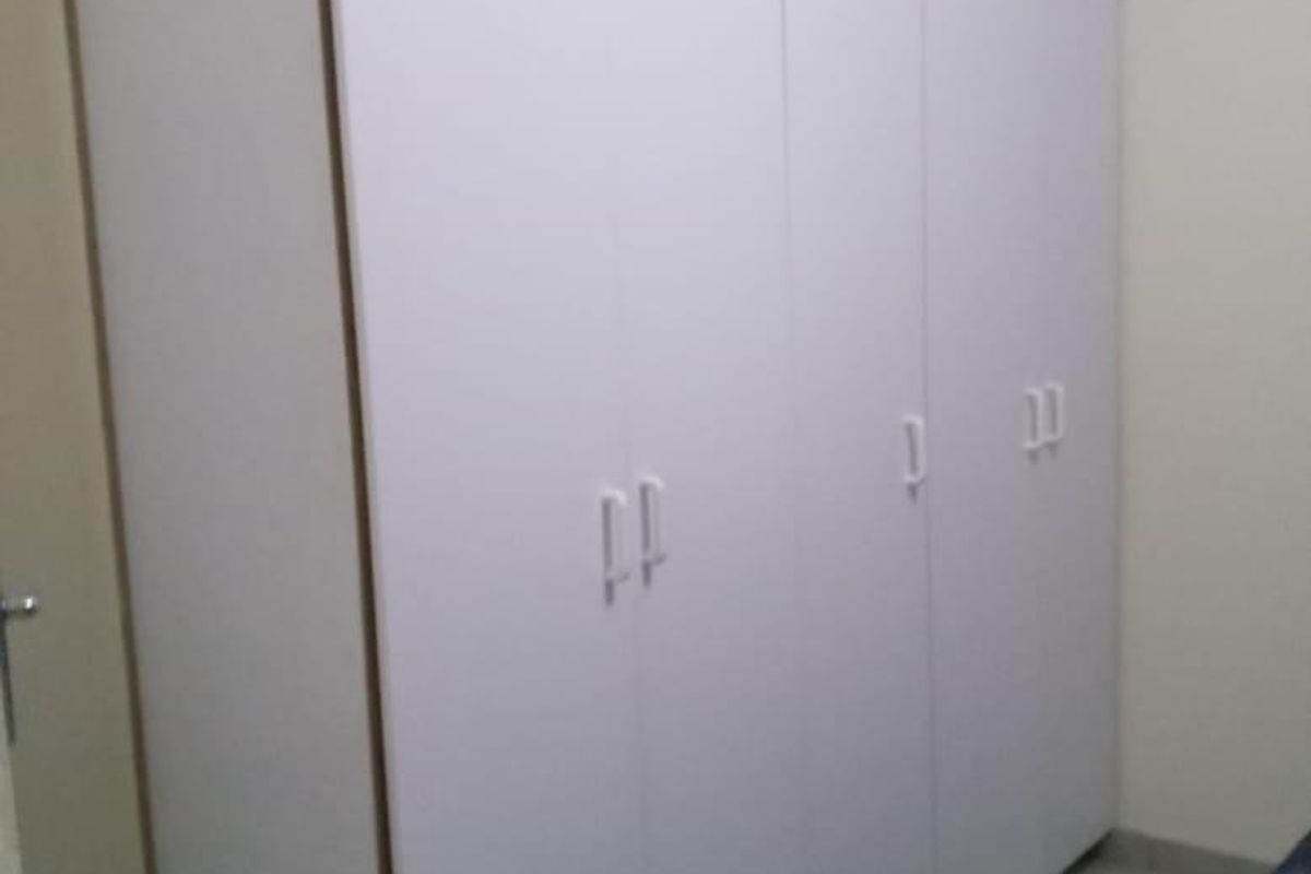 A bedroom featuring floor-to-ceiling white built-in cupboards providing ample storage space.