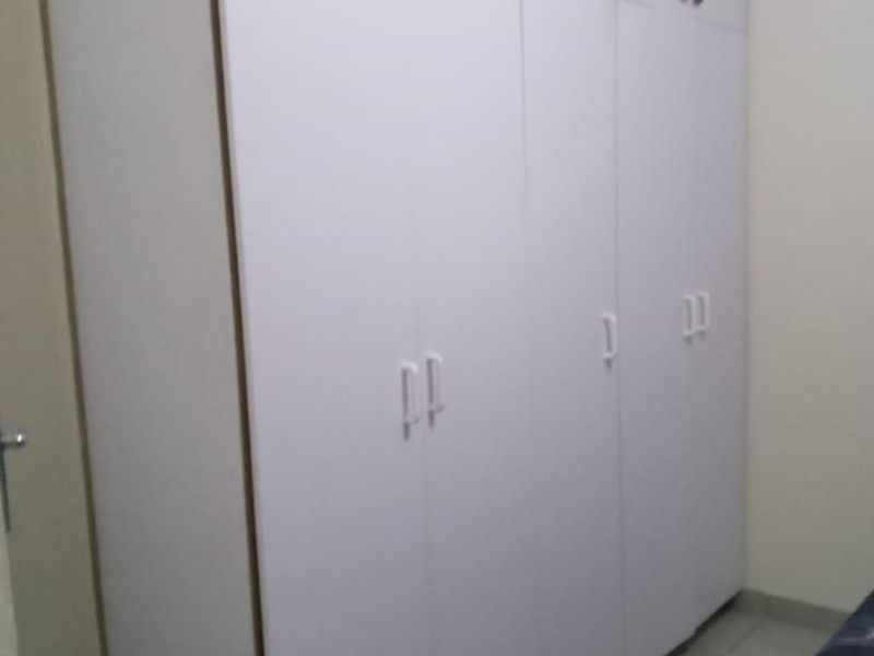 A bedroom featuring floor-to-ceiling white built-in cupboards providing ample storage space.
