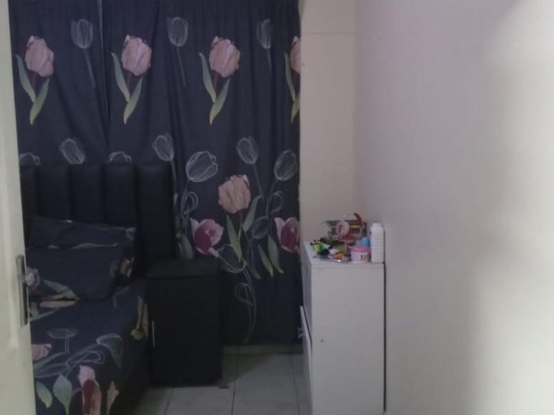 A bedroom featuring tiled flooring and a window covered by curtains.