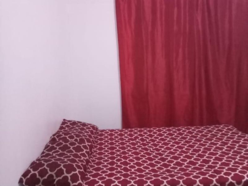 A simple bedroom space featuring plain walls and window coverings.