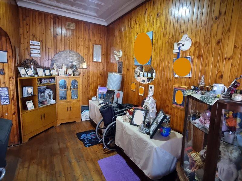 A living room featuring traditional timber wall paneling and decorative ceiling cornicing, offering a classic aesthetic with potential for modern updates.
