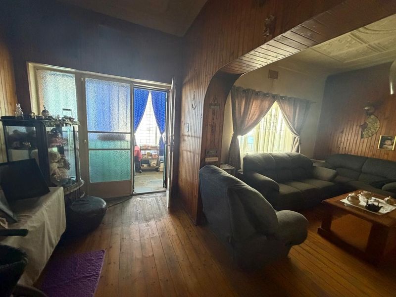 A living room featuring traditional timber wall paneling, original timber flooring, and an arched transition to an adjacent space.
