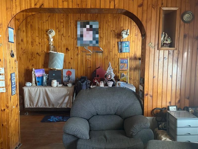 Living room featuring extensive timber wall paneling, an arched architectural opening, and a built-in wall niche.