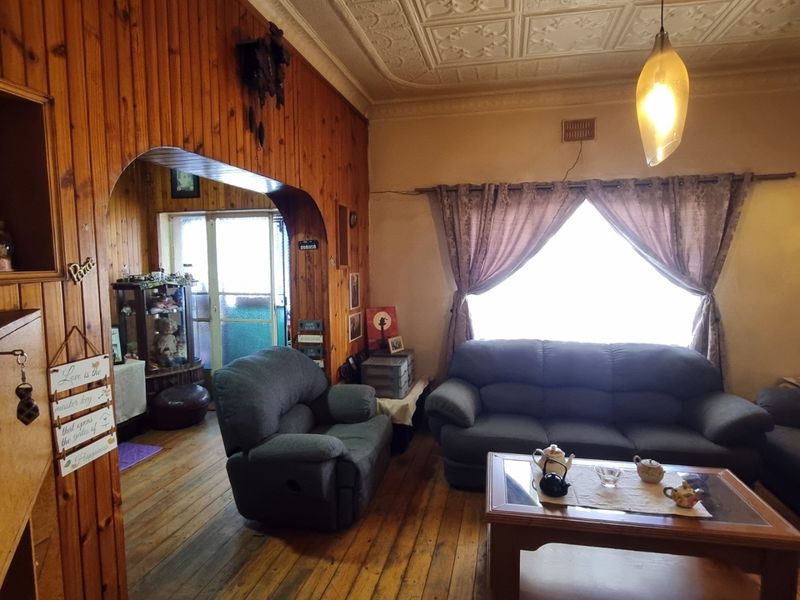 Living room featuring traditional timber wall paneling, a decorative pressed metal ceiling, and original timber flooring, offering a classic, character-filled space.