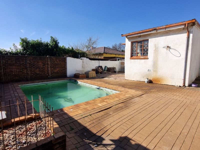 Outdoor pool area featuring brick paving and a boundary wall, requiring maintenance to the pool and exterior wall finishes.