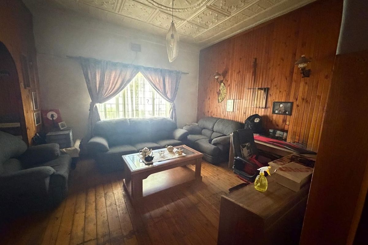 Living room featuring traditional pressed metal ceilings, timber wall paneling, and original timber flooring, offering a classic character aesthetic.