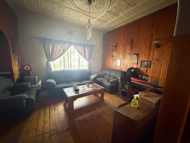 Living room featuring traditional pressed metal ceilings, timber wall paneling, and original timber flooring, offering a classic character aesthetic.