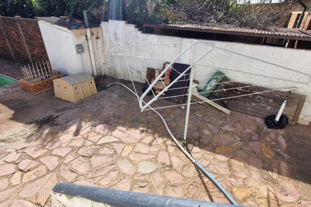 Rear outdoor area featuring stone paving and a boundary wall, offering potential for landscaping or patio development.