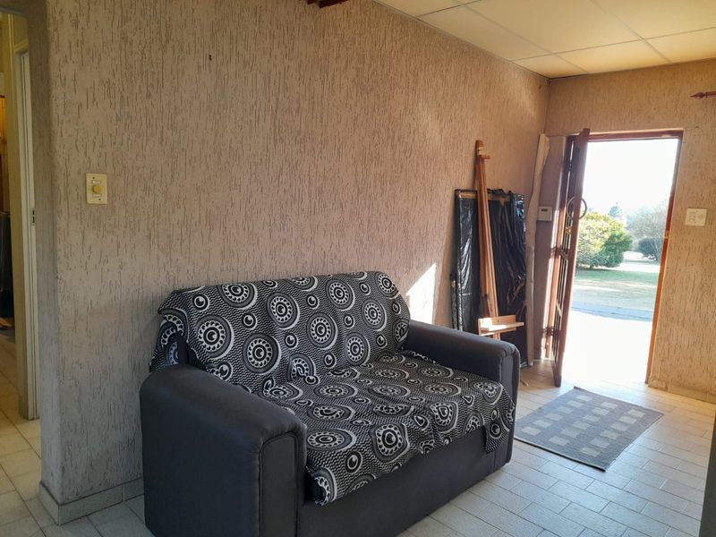 Living area featuring textured walls, tiled flooring, and a drop ceiling, with direct access to the exterior garden area.