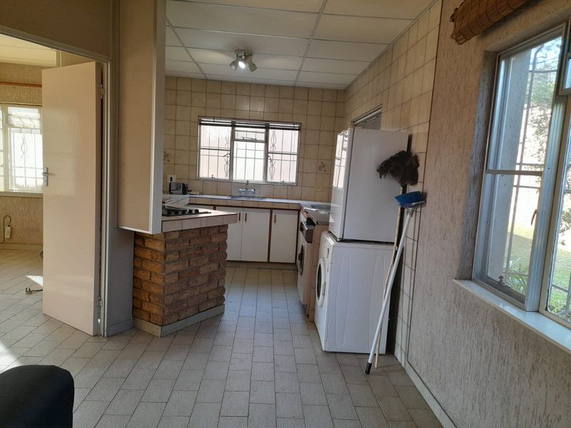 A functional kitchen featuring tiled splashbacks, built-in cabinetry, and a brick-base breakfast counter, offering potential for modernization and aesthetic updates.