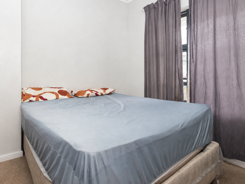 A simple bedroom featuring neutral wall finishes, carpeted flooring, and a window with curtains.