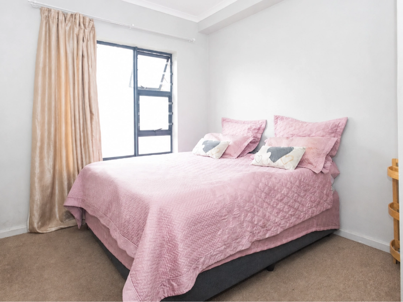 A well-maintained bedroom featuring neutral walls, carpeted flooring, and a built-in wardrobe with modern handles.