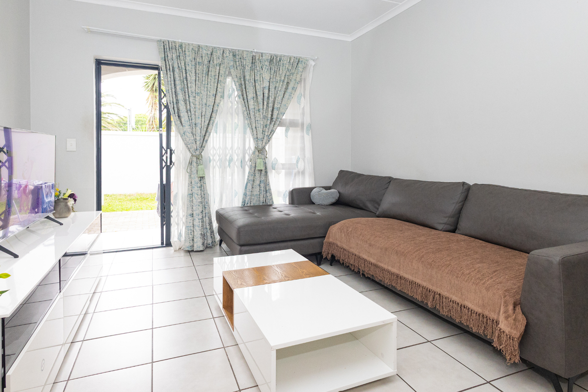 A bright living room featuring neutral tiled flooring and a sliding glass door providing direct access to the outdoor area.