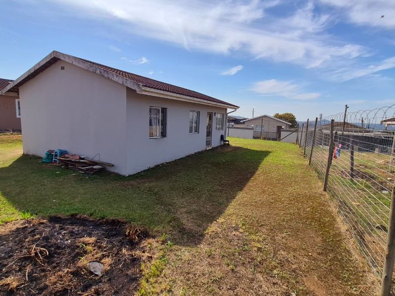 Rear view of the house featuring a tiled roof, security bars on windows, and a fenced yard with perimeter security.