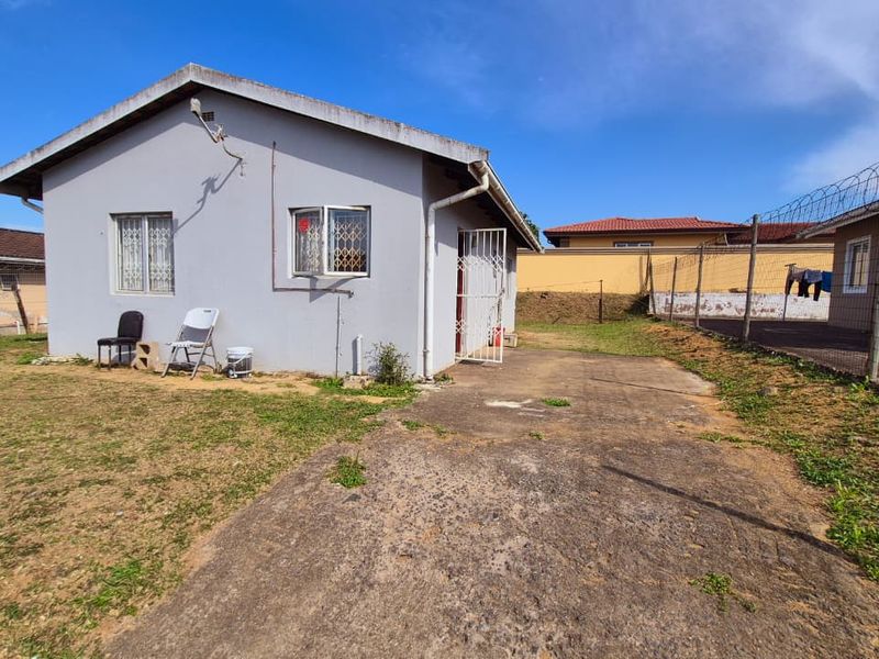 Rear view of the property featuring a concrete driveway, security gates, and perimeter fencing with razor wire.