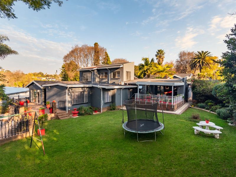 Rear view of the house featuring a spacious lawn, landscaped garden, and a covered patio area suitable for outdoor entertaining.