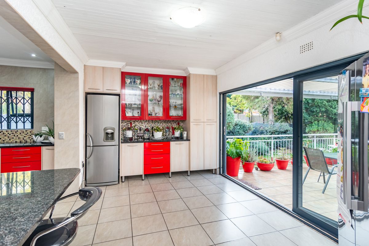 Kitchen featuring red and light wood cabinetry, granite countertops, mosaic backsplash, and large sliding doors opening to an outdoor patio area.