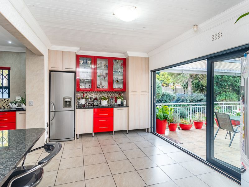 Kitchen featuring red and light wood cabinetry, granite countertops, mosaic backsplash, and large sliding doors opening to an outdoor patio area.