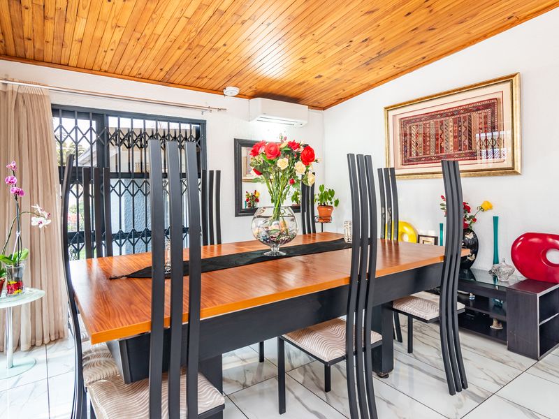 A dining room featuring marble-look floor tiles, a timber tongue and groove ceiling, and a wall-mounted split-system air conditioner.