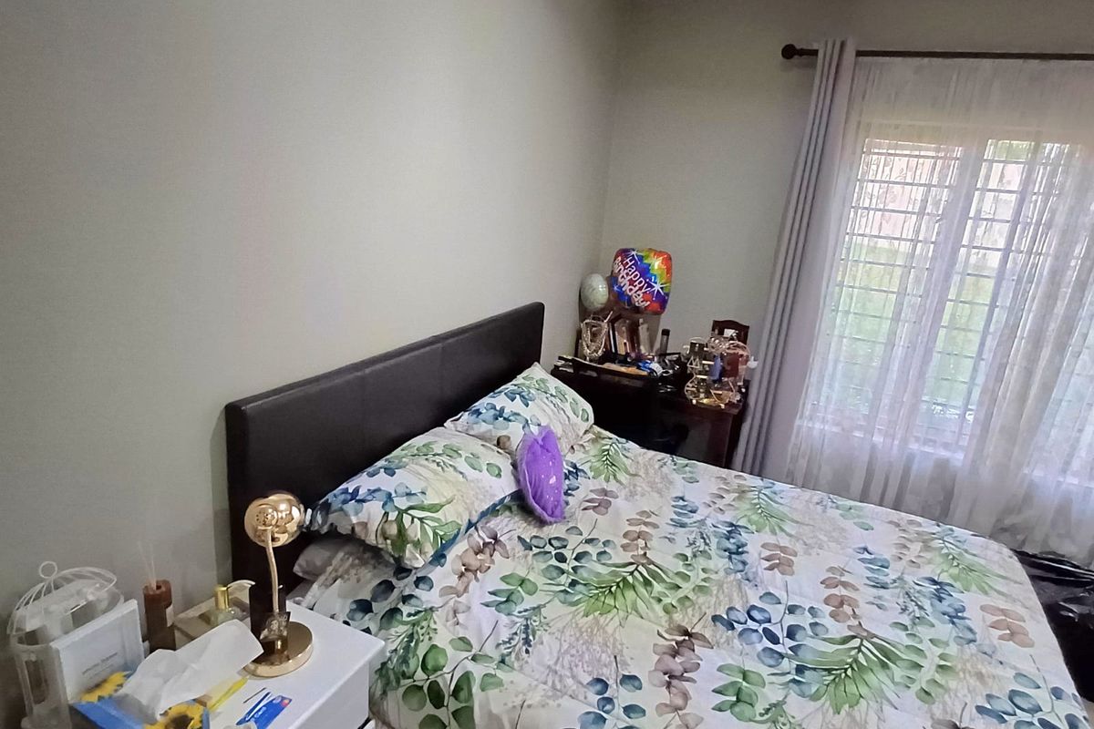 A functional bedroom featuring a window with security bars and neutral wall finishes, offering a comfortable space for rest.