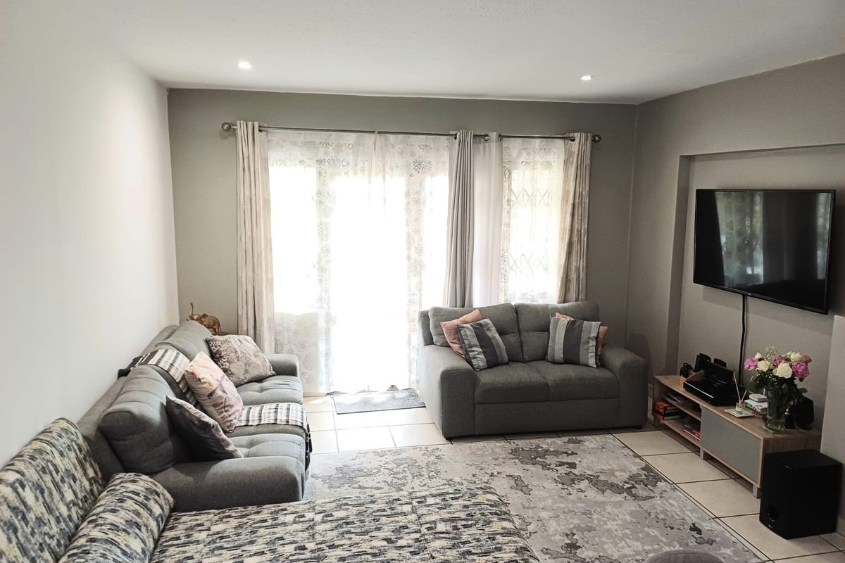 A comfortable living room featuring tiled flooring, recessed downlighting, and a sliding glass door providing access to the exterior.
