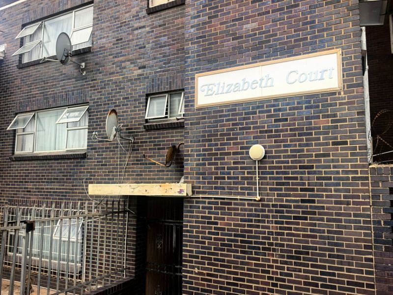 Exterior view of Elizabeth Court apartment building featuring a dark face brick facade, metal security gate, and building signage.