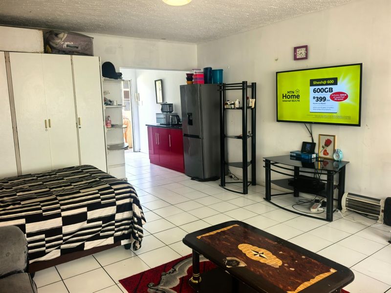 Open-plan living area featuring tiled flooring, built-in wardrobe storage, and an adjoining kitchen space with red cabinetry.