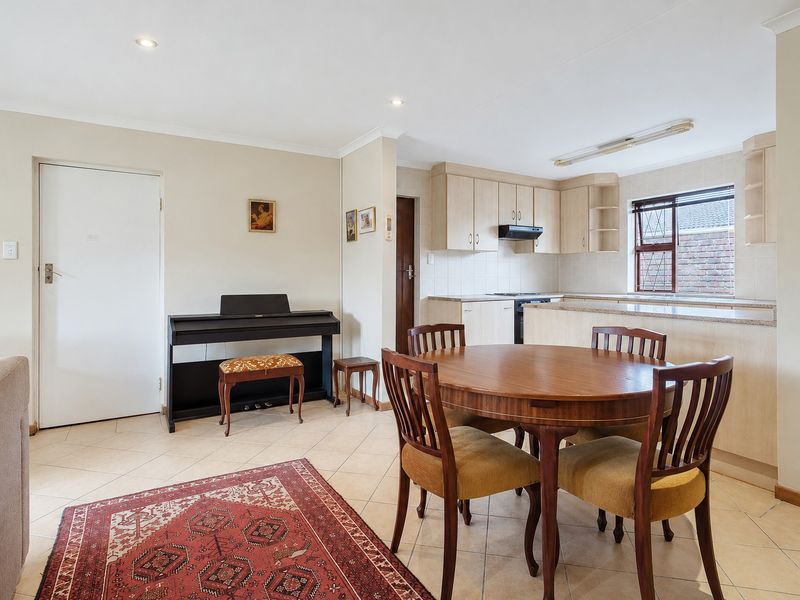 Open-plan living and dining area featuring tiled flooring and a functional kitchen with built-in cabinetry and laminate countertops.