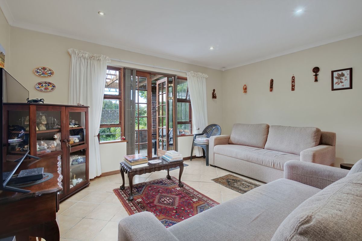 A comfortable living room featuring tiled flooring, recessed lighting, and wooden framed glass doors providing direct access to the outdoor patio area.